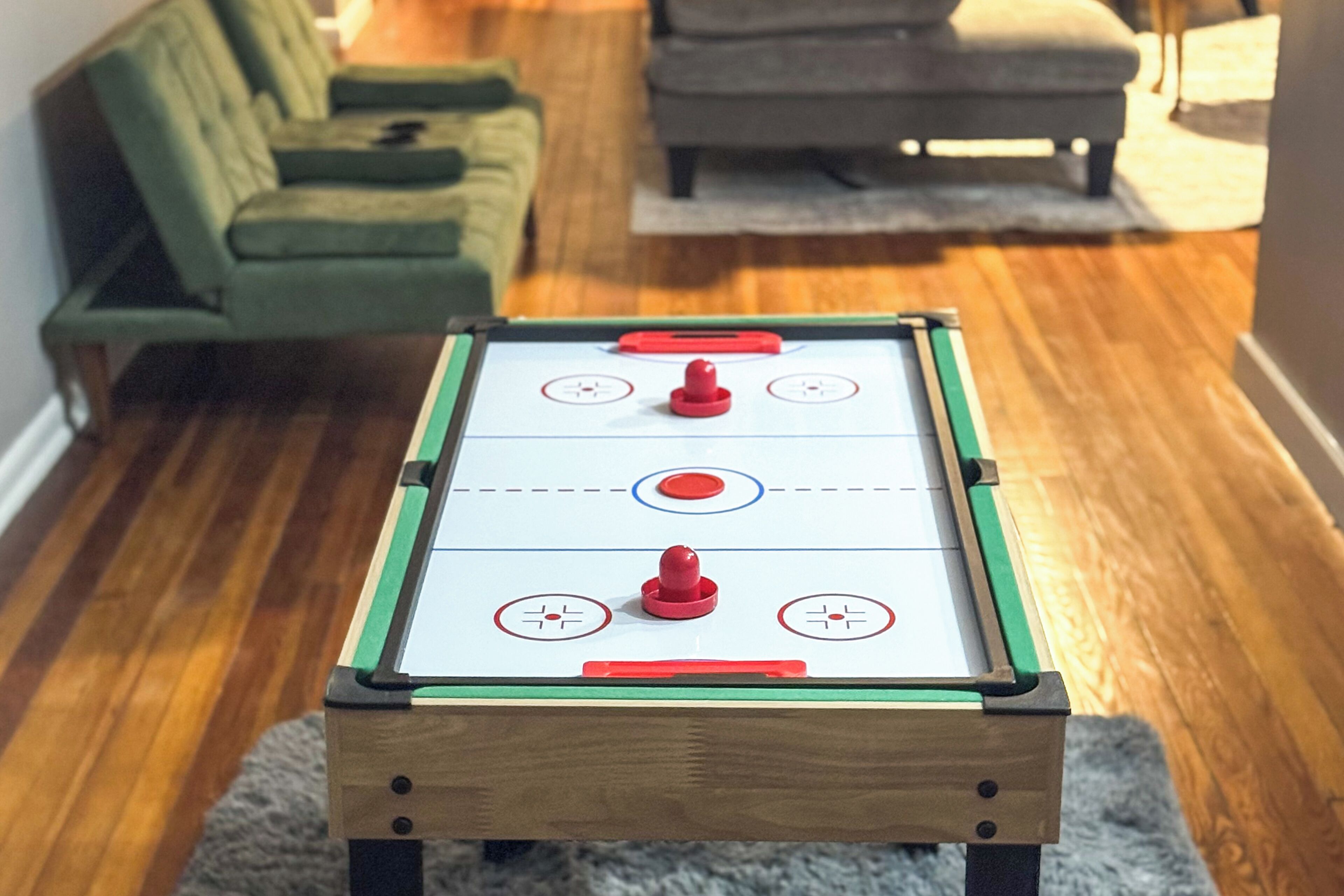 Une table de billard recouverte d’une nappe verte et blanche, entourée d’un parquet.