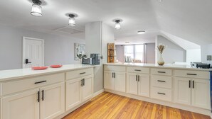A spacious kitchen with white cabinetry, wooden flooring, and pendant lighting. - Walk to Coventry Village: Charming Top-floor Unit! (Cleveland Heights)