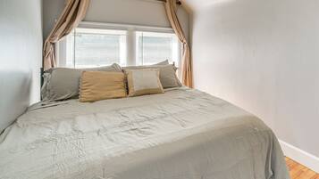 Un dormitorio con cama con dosel, una ventana con persianas y suelo de madera.