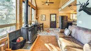 A rustic cabin interior with a fireplace, wooden floors, a leather sofa, and a deer head mounted on the wall. - Fire Pit & Peak Views: Gold Camp Area Cabin (Cripple Creek)