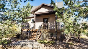 A two-story house with a covered porch, wooden stairs, and a chimney. - Fire Pit & Peak Views: Gold Camp Area Cabin (Cripple Creek)