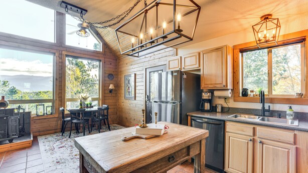 A rustic kitchen with wooden cabinets, a large island, and a view of the outdoors. - Fire Pit & Peak Views: Gold Camp Area Cabin (Cripple Creek)