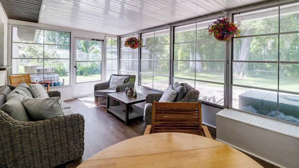 A sunroom with wicker furniture, large windows, and hanging flower baskets. - Bring Your Boat! Canal-front Tavares Home w/ Dock (Tavares)