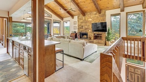 A spacious living area with a stone fireplace, a large TV, and a wooden ceiling. - Luxury Home w/ Hot Tub & Mtn Views in Angel Fire! (Angel Fire)