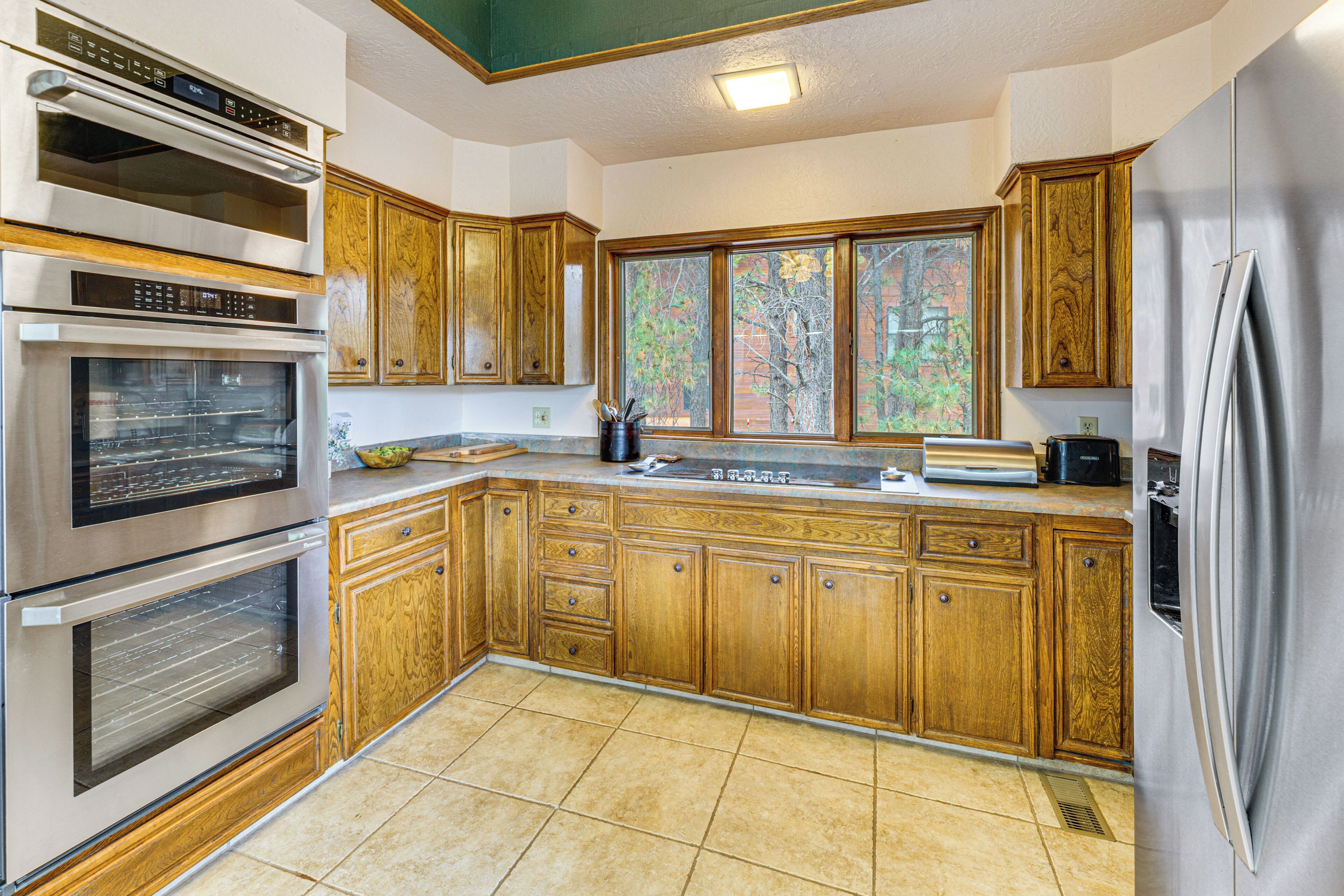 A kitchen with wooden cabinets, stainless steel appliances, and a large window.