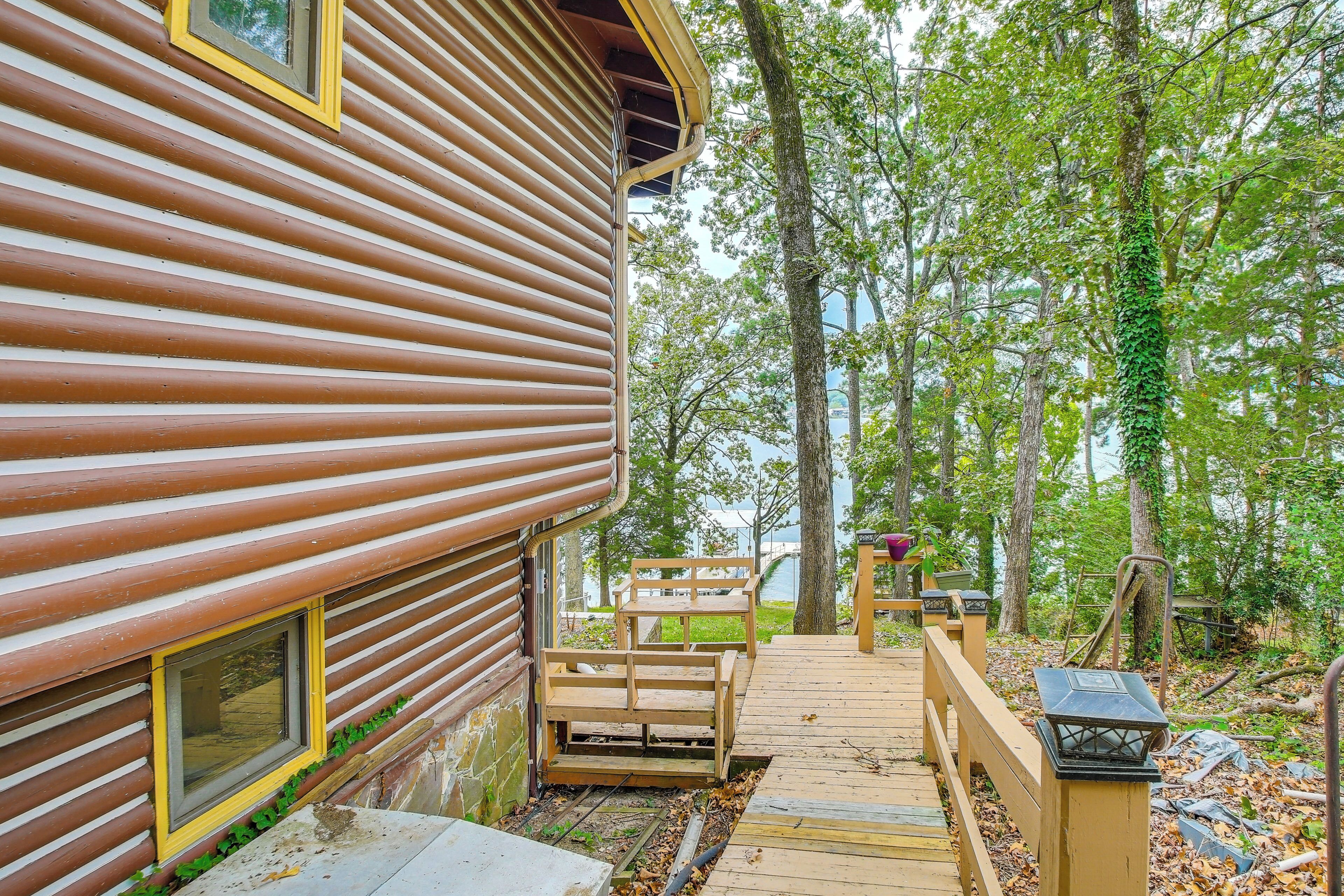 A wooden cabin with a deck leading to a picnic table and benches.