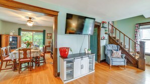 A dining area with a wooden table and chairs, a TV mounted on the wall, and a staircase leading to another level. - 1 Mi to Dtwn Binghamton: Pet-friendly Home w/ Deck (Binghamton)