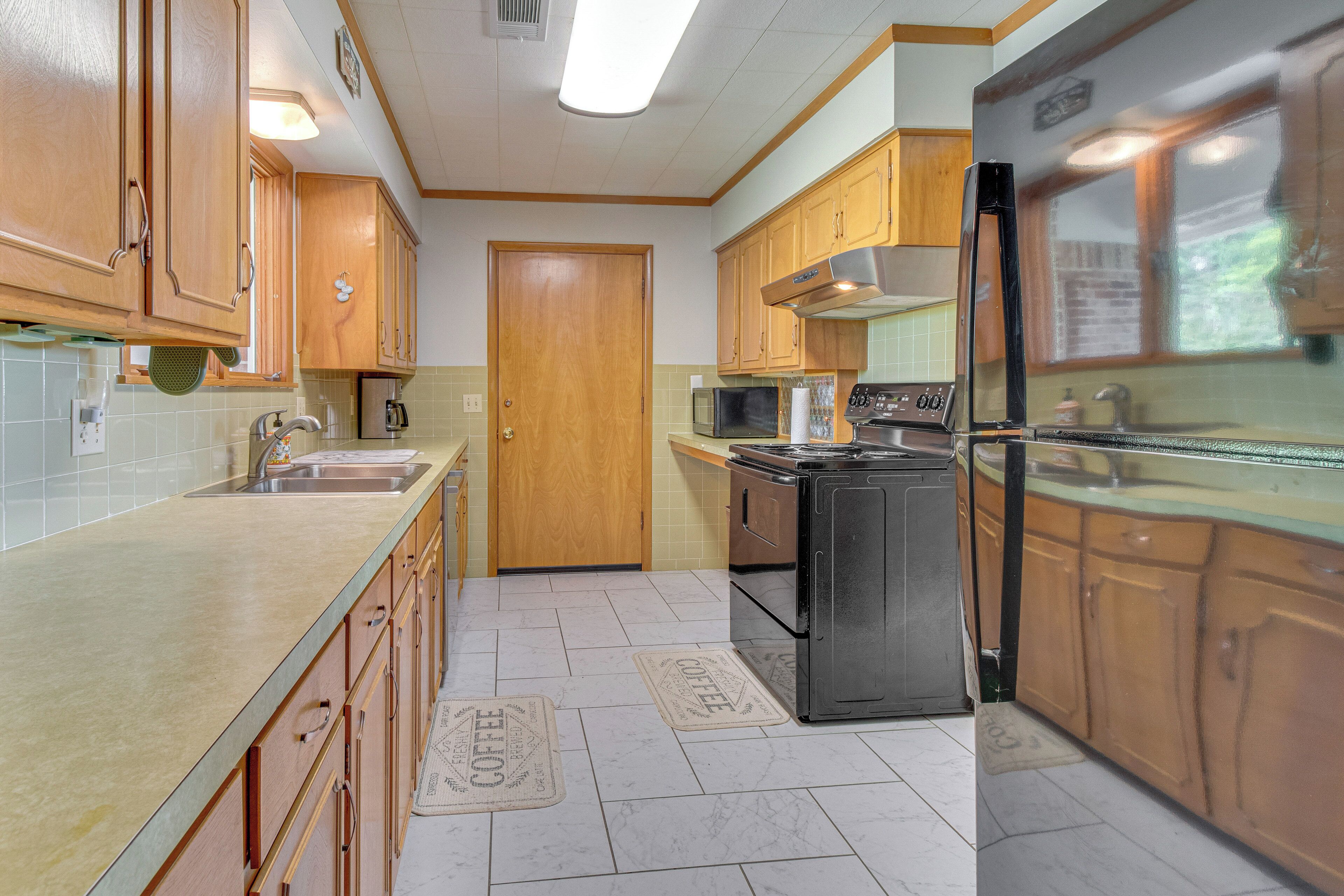 A kitchen with wooden cabinets, a stainless steel refrigerator, a microwave, and a stove.