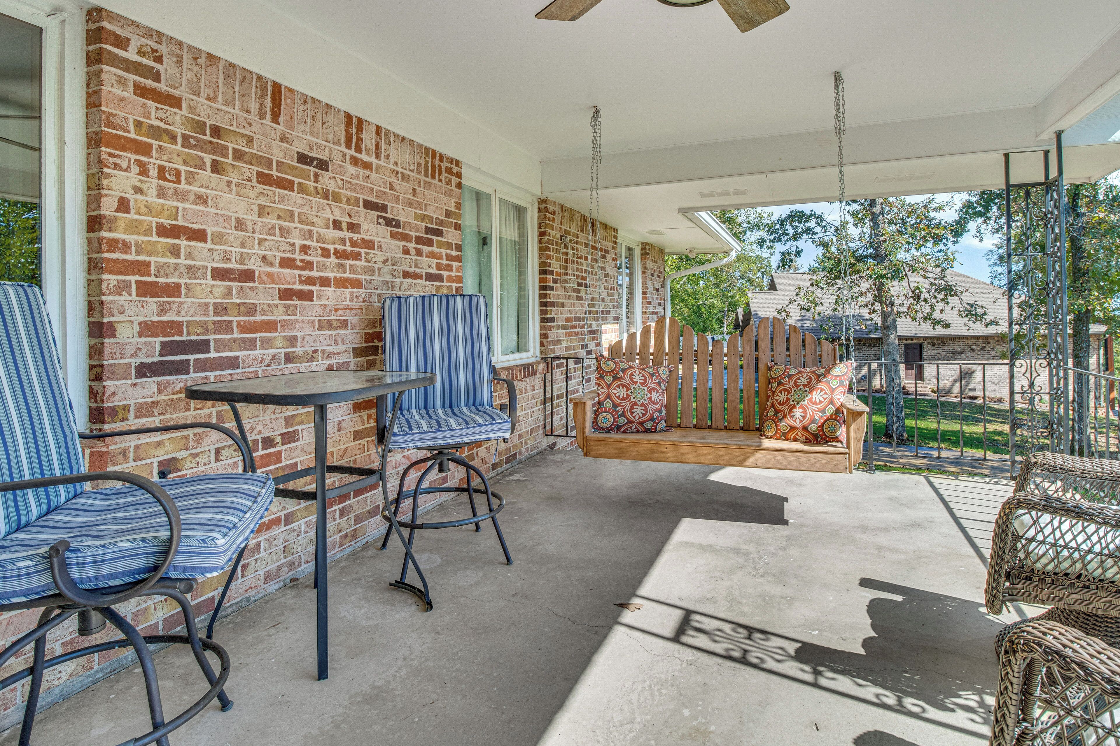 A covered patio area with a brick wall, a table with chairs, and a cushioned seating area.
