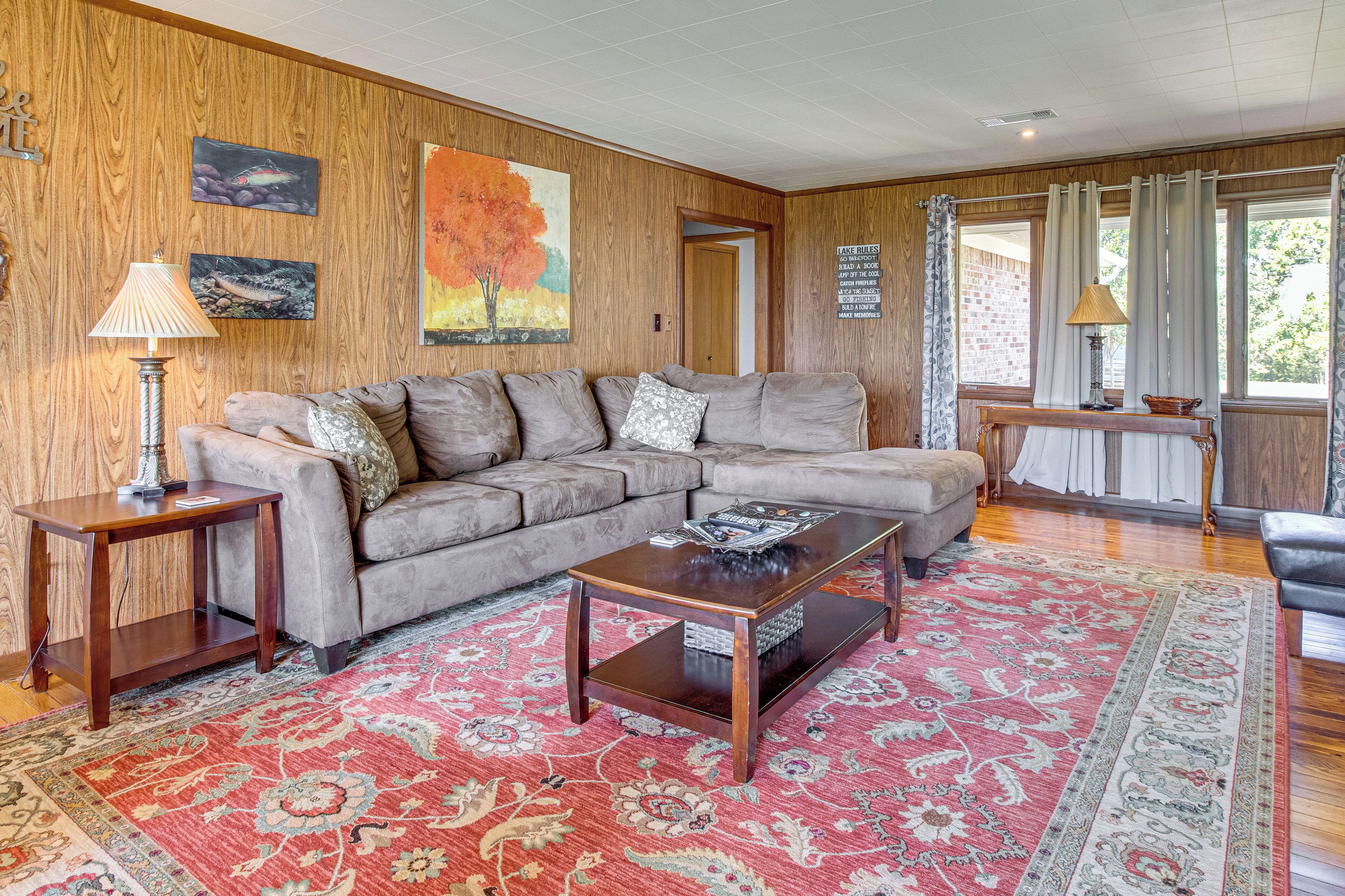 A living room with a sectional sofa, a coffee table, a rug, and wooden walls.