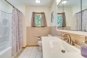 A bathroom with a bathtub, toilet, sink, and window with curtains. - 1 Mi to Norfolk Lake! Anglers Escape w/ Mtn Views (Mountain Home)