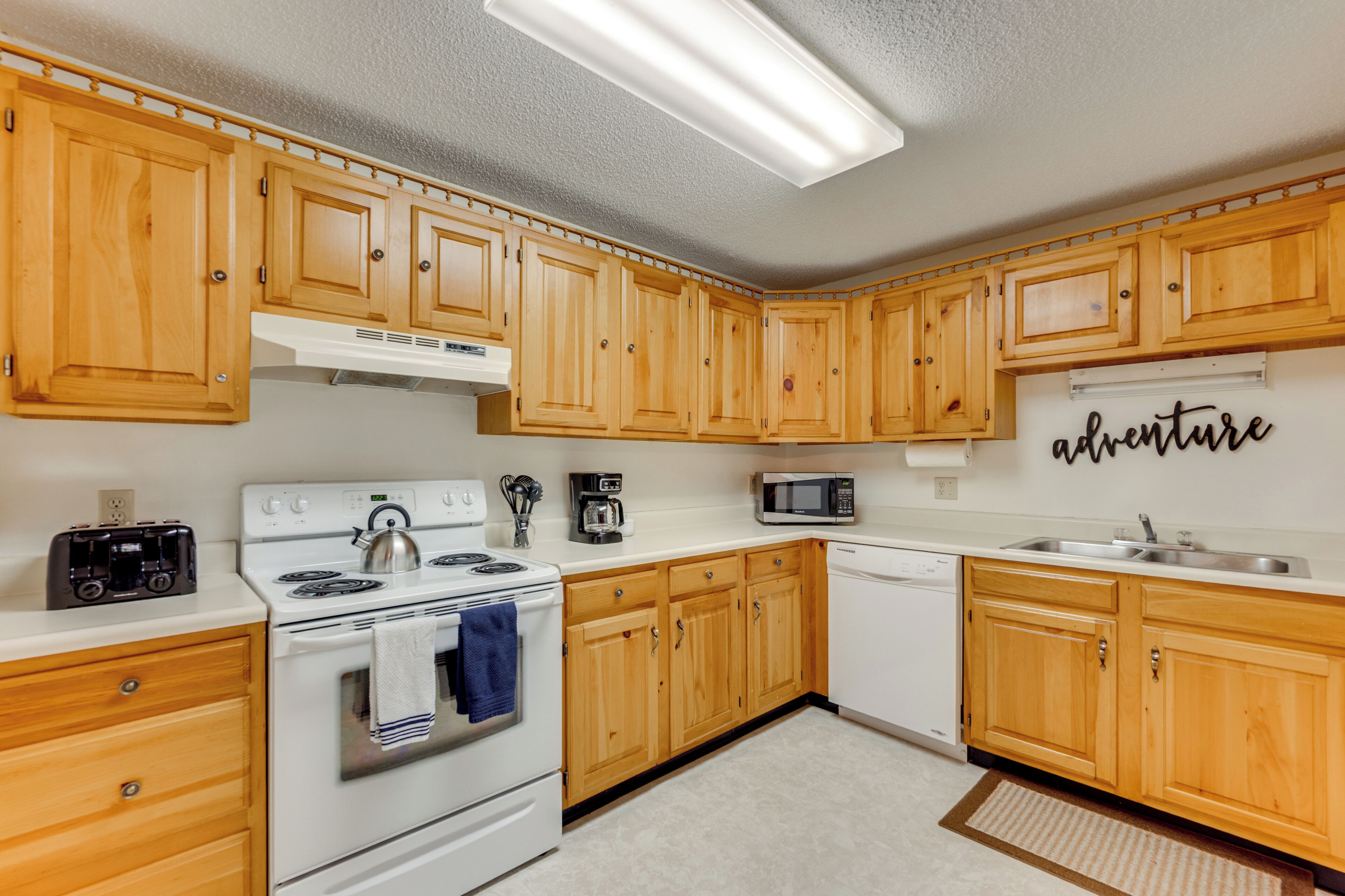 A kitchen with wooden cabinets, a stove, a microwave, and a coffee maker.