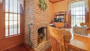 A cozy room with a brick fireplace, wooden furniture, and a brick wall. - Walk to Downtown: Historic Home in Edentons Heart (Edenton)