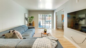 Ein modernes Wohnzimmer mit einem grauen Sofa, einem Couchtisch und einem großen Fernseher an der Wand.