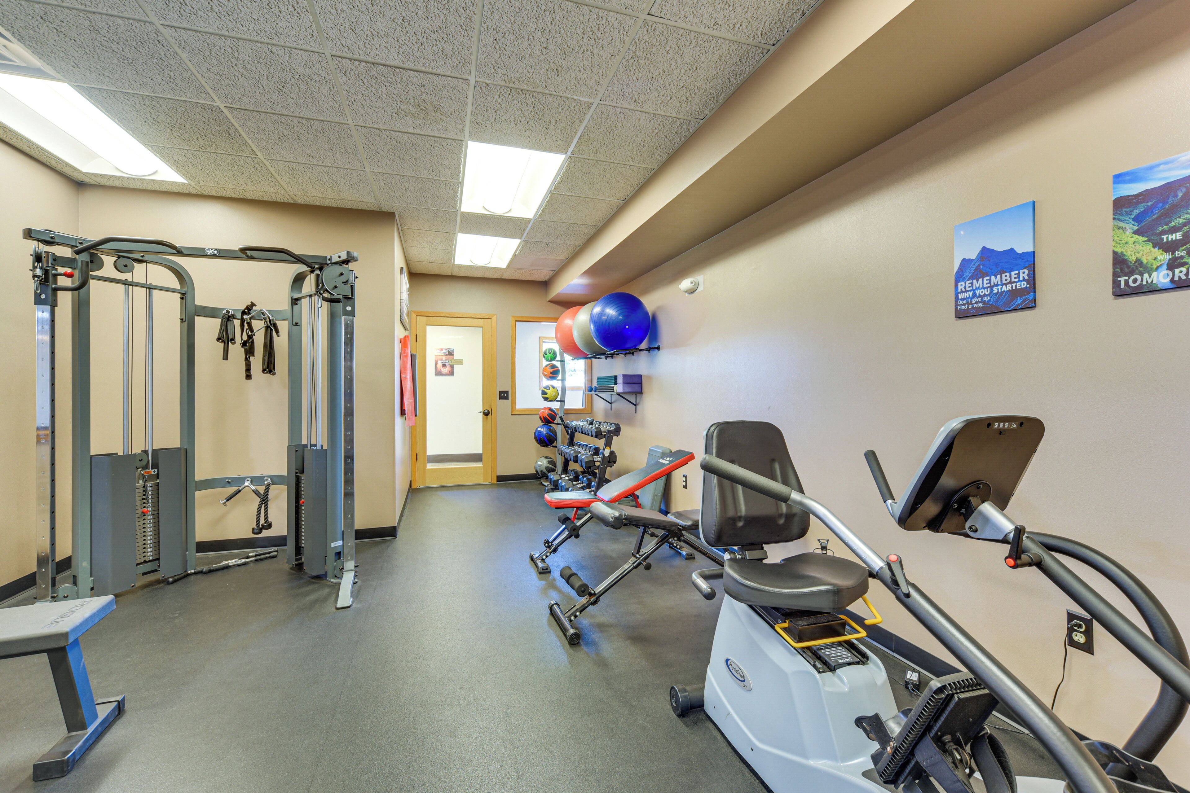 Une salle de sport équipée de matériel d’exercice, d’un tapis de course et ornée d’affiches motivantes.
