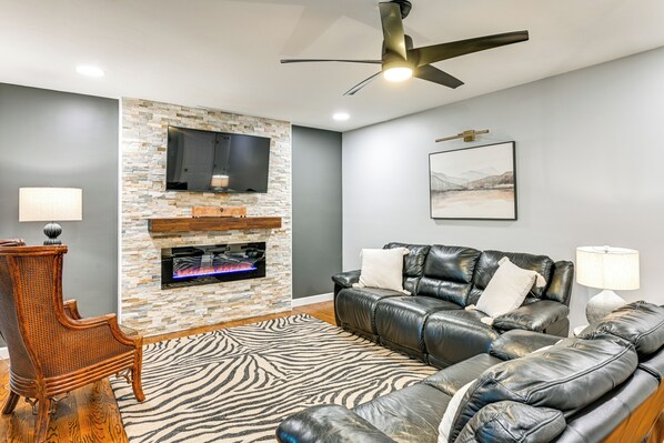 Ein modernes Wohnzimmer mit Kamin aus Stein, Ledersofa und Teppich mit Zebra-Muster.