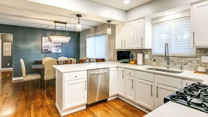 A modern kitchen with white cabinetry, a stainless steel dishwasher, and a gas stove.