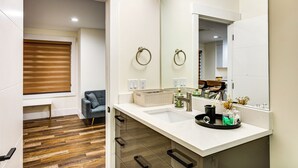 Un baño moderno con encimera blanca, un espejo grande y suelo de madera.