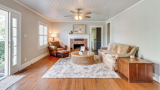 A living room with hardwood floors, a ceiling fan, a fireplace, a sofa, and a coffee table. - Walk to Dtwn Hahira: Inviting Home w/ Pool & Yard! (Hahira)