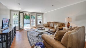 A spacious living room with a leather sofa, a coffee table, and a TV on a wooden cabinet. - Walk to Dtwn Hahira: Inviting Home w/ Pool & Yard! (Hahira)