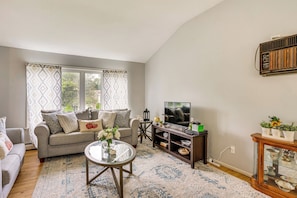A living room with a sofa, coffee table, TV, and decorative items. - Family Home Near LIE & Blydenburgh Co Park (Hauppauge)