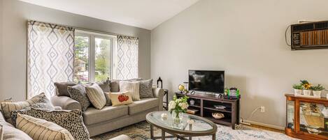 A living room with a sofa, a glass coffee table, a TV, and a wooden cabinet.