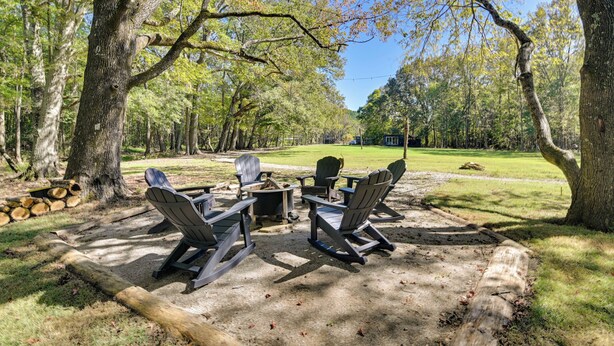 A campsite with Adirondack chairs, a fire pit, and a table set up on a clear day.