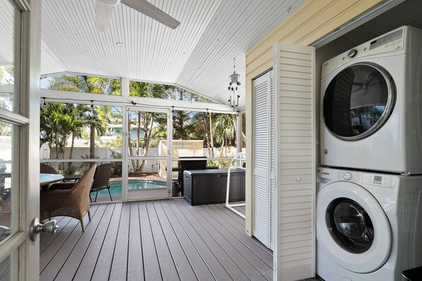 Un espacio exterior techado con lavadora, piscina y mobiliario de exterior.
