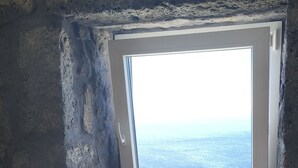 A workspace with a laptop, papers, and a view of the sea through a window.