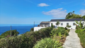 A coastal house with a patio overlooking the sea, surrounded by lush greenery. - Bioma Adega - Gourmet Stay (Foros)