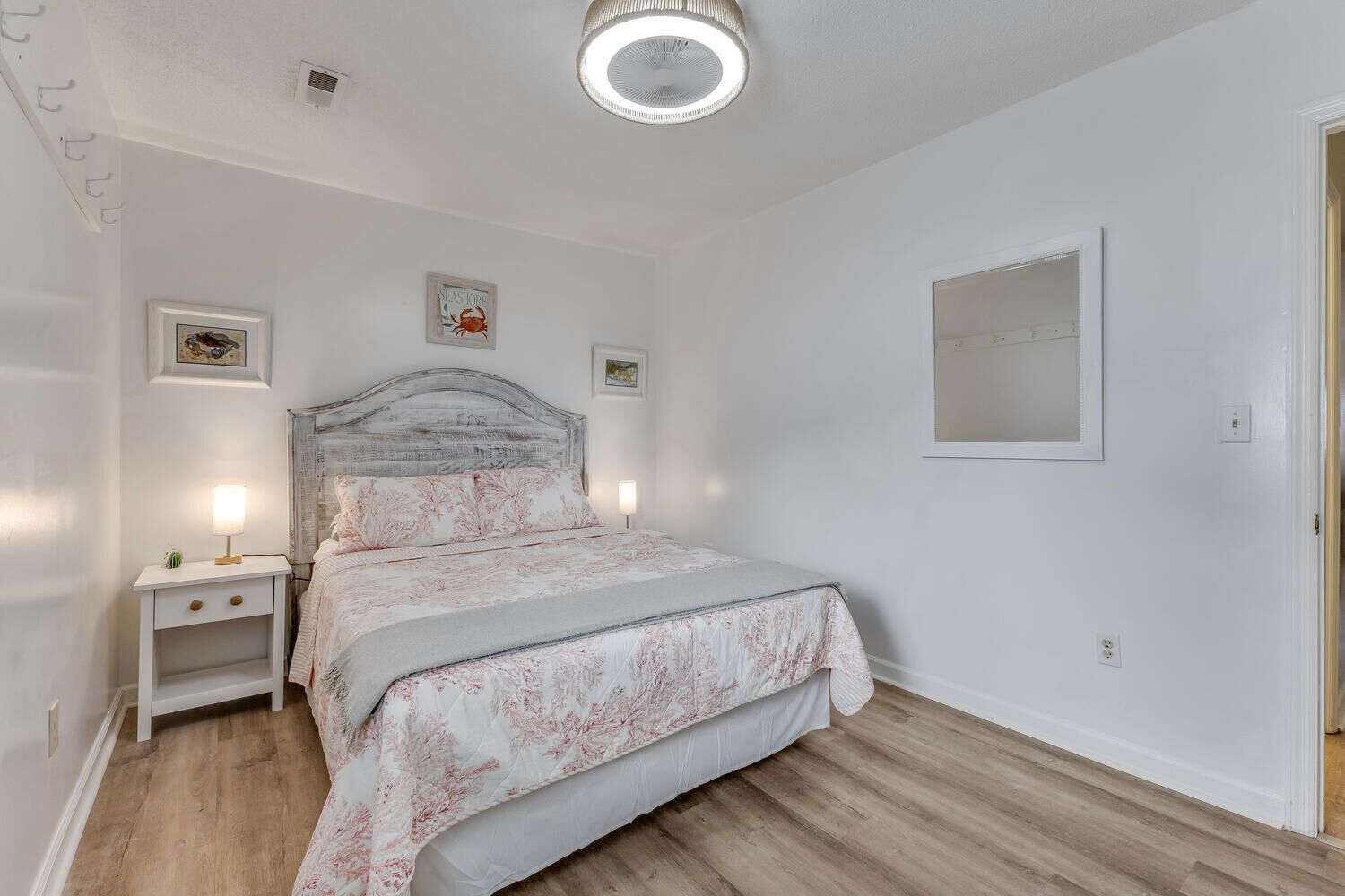 A bedroom with a bed, bedside tables, a ceiling light, and framed pictures on the wall.