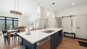 A modern kitchen with a large island, built-in appliances, and a dining area with a view.