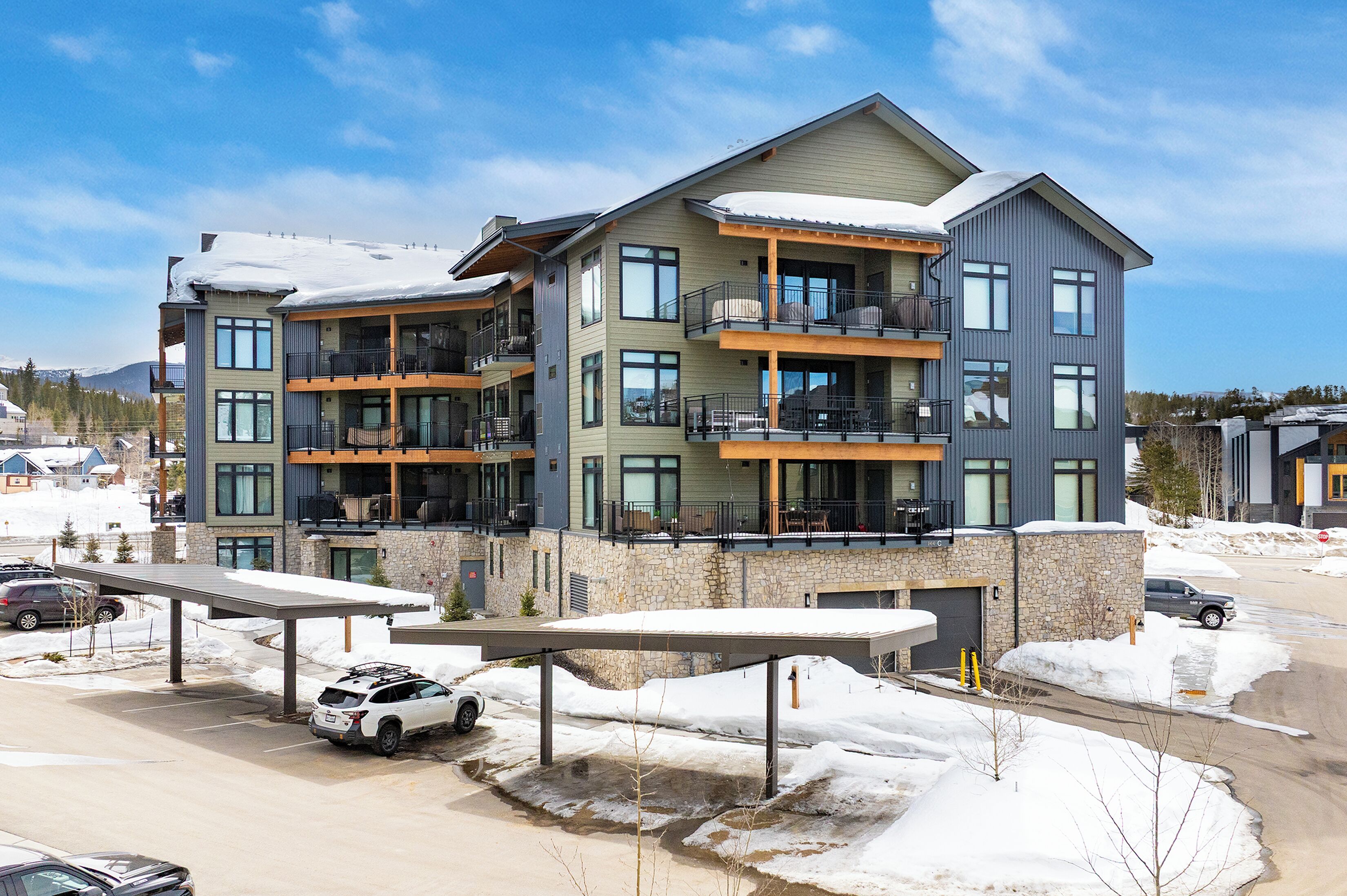 A multi-story hotel with balconies, a covered parking area, and a view of the surrounding snowy landscape.