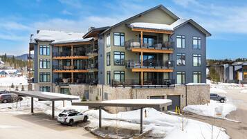 A multi-story hotel with balconies, a covered parking area, and a view of the surrounding snowy landscape.