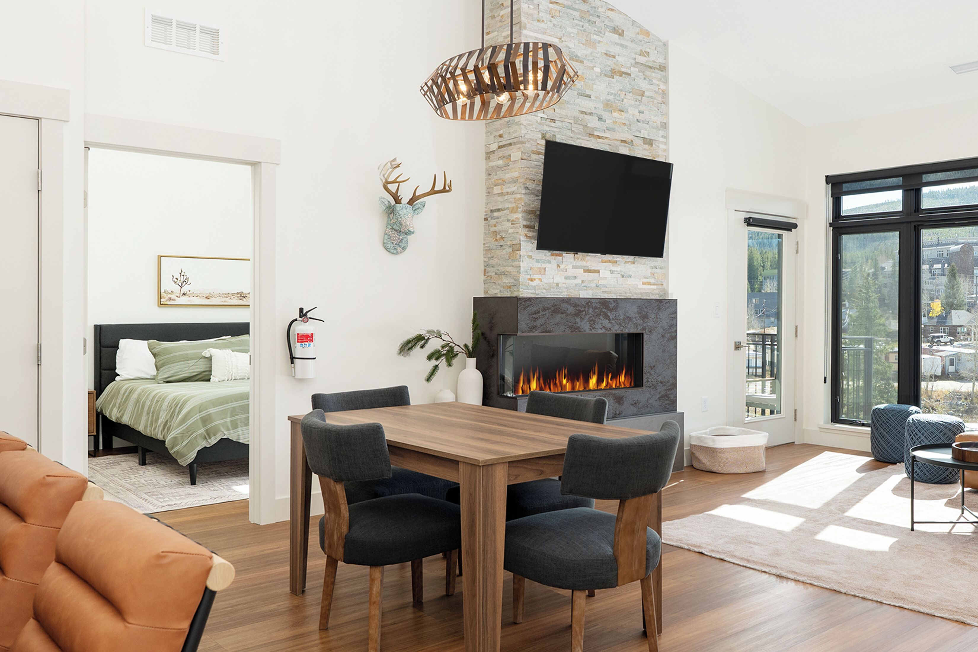 A modern living room with a fireplace, a dining area, and a view of the outdoors.