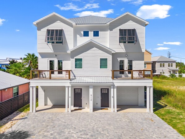 Une maison à deux étages avec un porche à l’avant, un garage et une allée couverte.