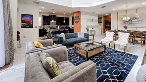 A spacious living room with a large sofa, a coffee table, and a dining area with chairs. - Luxe & Leisure Lodge: Free Resort Access! (Davenport)