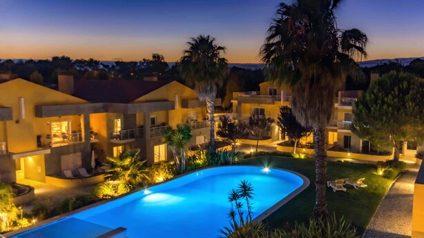 Ein Resort mit Swimmingpool, mehreren Gebäuden und Palmen.