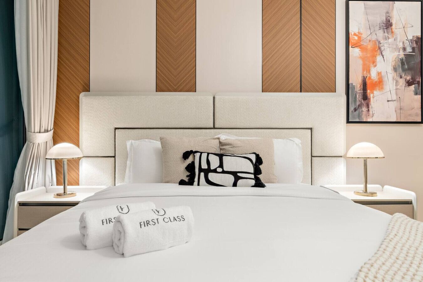 Ein Hotelzimmer mit Bett, zwei Nachttischlampen, einem Kopfteil und einem Bild an der Wand.