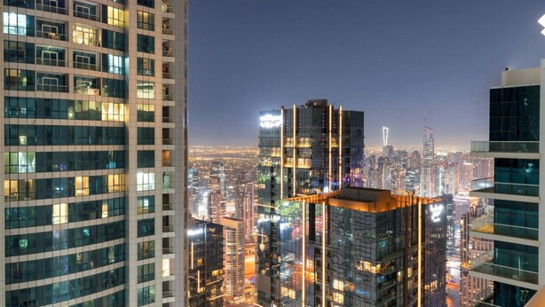 A high-rise building with multiple floors, large windows, and a cityscape in the background.