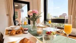 A breakfast setup with croissants, strawberries, a vase of flowers, and a view of the city through large windows. - PrivateTerrace Opposite PiccadillyLine • 20min SOHO, Oxford Street & Sightseeing (Uxbridge)