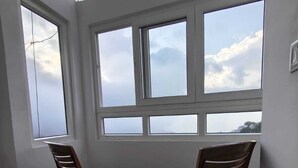 Ett rum med ett takfönster, två trästolar och utsikt över himlen genom flera fönster.