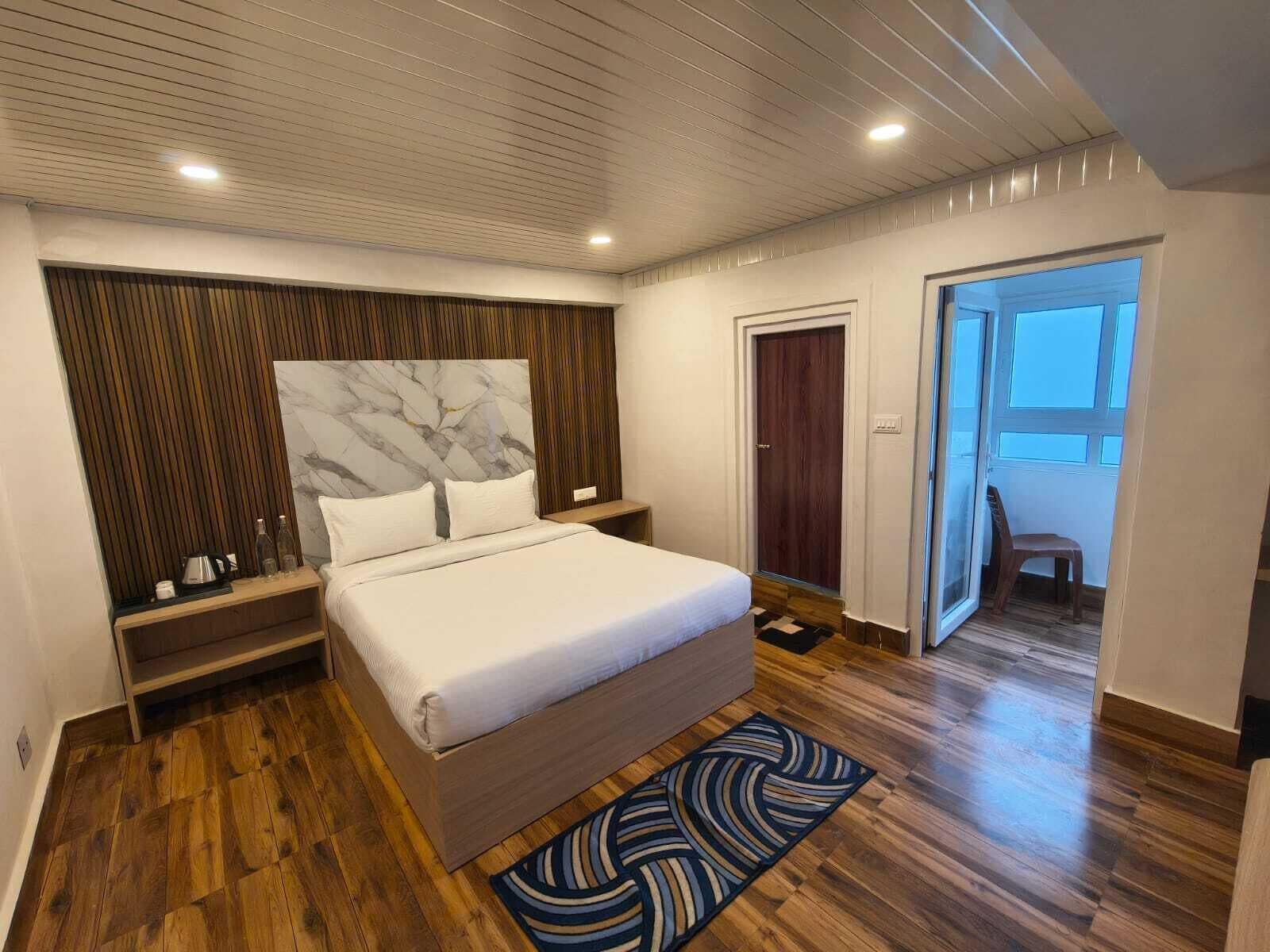 Ein modernes Schlafzimmer mit einem großen Bett, Holzboden, einem Marmorkopfende und Blick ins Freie.