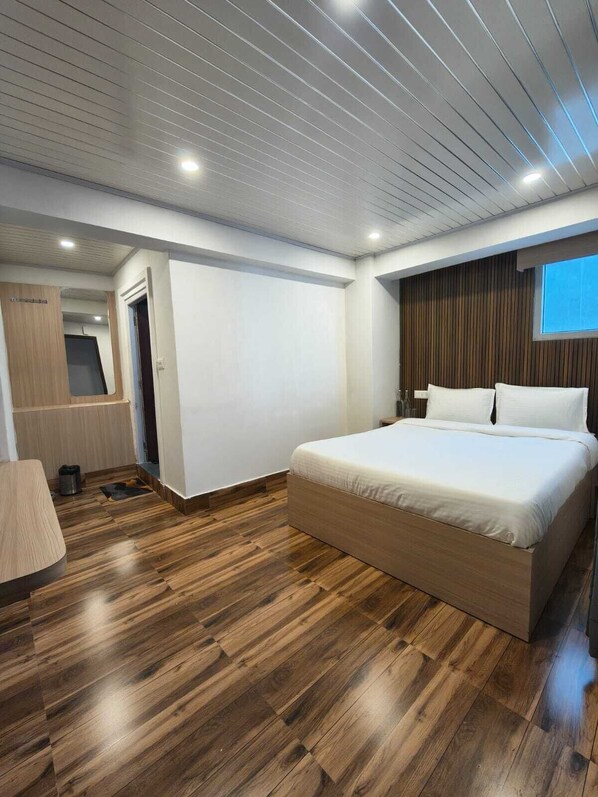 A modern bedroom with a large bed, wooden flooring, and a built-in wardrobe. - PINEVIEW ESCAPES (Darjeeling)