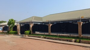 A building with a gated entrance, brick pillars, and a metal roof. - North Stay Inn (Livingstone)