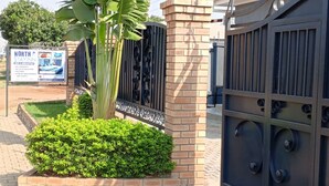 A gated entrance with a brick pillar, a metal gate, and a signboard advertising a stay-in-nor hotel. - North Stay Inn (Livingstone)