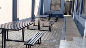 A corridor with multiple black metal tables and benches arranged along a tiled floor. - North Stay Inn (Livingstone)