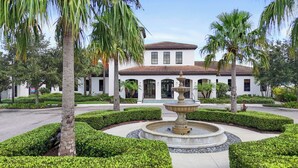 A building with a fountain, surrounded by well-maintained hedges and palm trees. - Cinderella’s Castle Retreat, Private Pool, Pokémon Room, Minutes to Disney! (Four Corners)