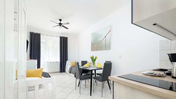 Eine moderne Küche mit Essbereich, einem weißen Sofa und einem Deckenventilator.