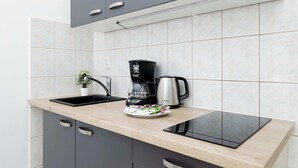 Eine moderne Küche mit einer schwarzen Kaffeemaschine, einem Wasserkocher und einem Tablet auf der Arbeitsfläche.